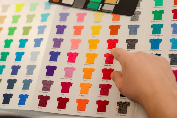 Hombre recortado mano elegir muestras plantillas multicolor publicidad camisetas paleta película membrana. Producción textil — Foto de Stock