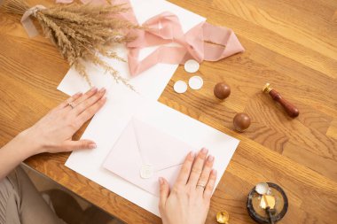 Kadın elinin yabani otları otlatırken çekilmiş resmi, pembe kurdele ve mühür ağdasıyla süslenmiş. Üst görünüm