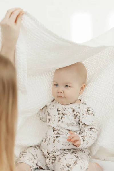 Ritratto di bambino bambino sorridente, paffuto, con gli occhi azzurri, coperto da una coperta di cotone bianco seduta sulla biancheria da letto bianca. — Foto Stock