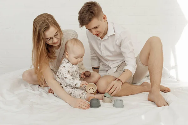 Jovem família fabulosa sorridente com bebê infantil gordo bonito brincando com tigelas de silicone coloridas modernas de tamanho diferente. — Fotografia de Stock