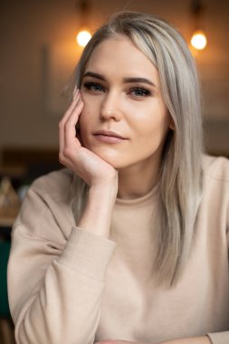 Dikey gülümseyen güzel, çekici, makyajlı, kameraya bakan, eline yaslanan sarışın kadın. İlk randevu. Kapat.