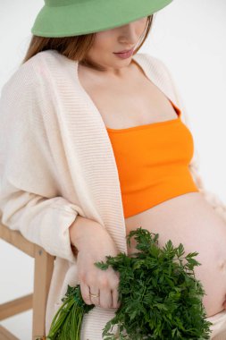 Dikey trend hamile kadın, yeşil şapkalı saklanan yeşil şapkalı bir demet yeşille kalıyor. Sağlıklı, akne derisi yemiyor.