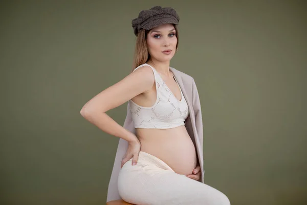 모직 모자를 쓰고 레이스 옷을 입고 의자에 앉아 있는 임신 한 건강 한 여성. 배, 배를 잡고. 출산을 준비하라. — 스톡 사진