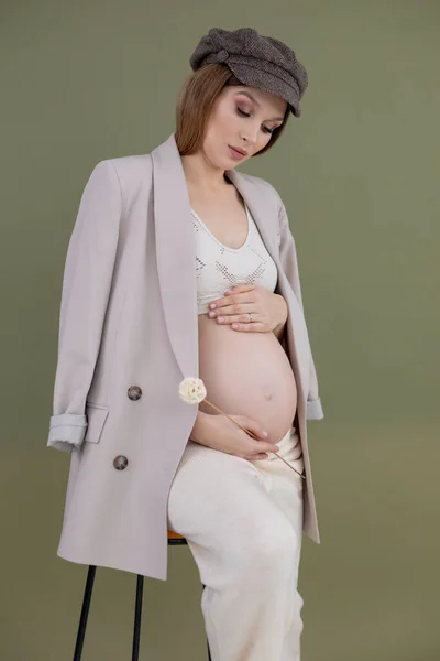 Вертикальное фото модной беременной женщины в кепке, сидящей на барном стуле. Держу палку декора. Проблема гипертонии — стоковое фото