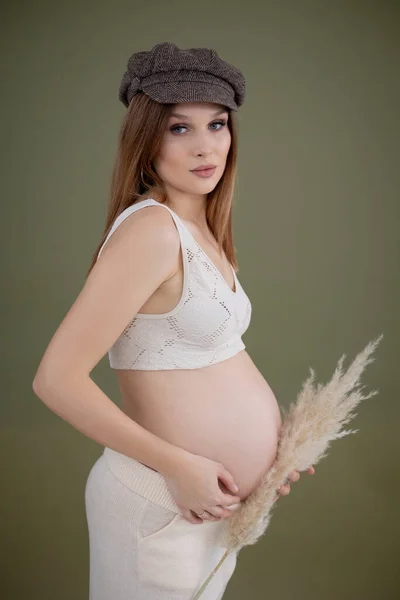 Függőleges fotó egy divatos terhes nőről lensapka, csipke ruha. Tartom a hasam, a hasam. Mosott tök cellulitisz — Stock Fotó