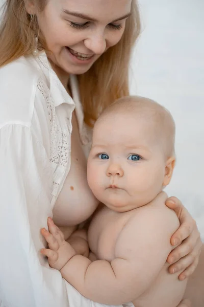 Vertical photo of smiling blond gentle woman with bare chest, holding little baby eating, breastfeeding before sleep — Stock Photo, Image