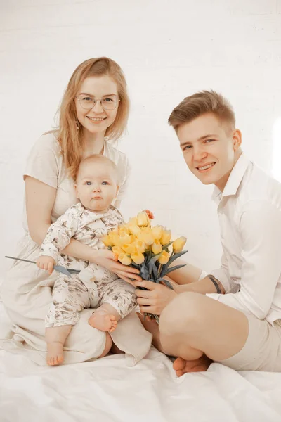 Vertikales Porträt beschnitten glückliche Familie, Blick Kamera, Umarmung. Frohe Feiertage, Strauß gelbe Tulpen — Stockfoto