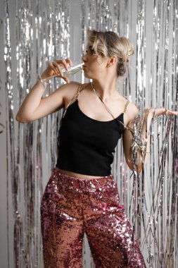 Mutlu, sarışın, sarhoş bir kadının dikey portresi, dans eden, içen, doğum günü gümüşü ışıltısını kutlayan