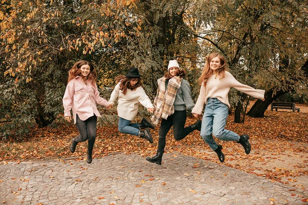 四个亲密的女性朋友大学毕业后重逢，在秋天的花园里共度时光，跳高空 — 图库照片