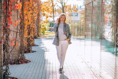 Sarışın, kendine güvenen bir iş kadınının taş yol akçaağacı portresi. Yansıma binası cam aynası