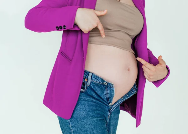 Nerozpoznatelná těhotná žena v nezapnutém denimu ukazující prsty na velké břicho, problémy během těhotenství — Stock fotografie