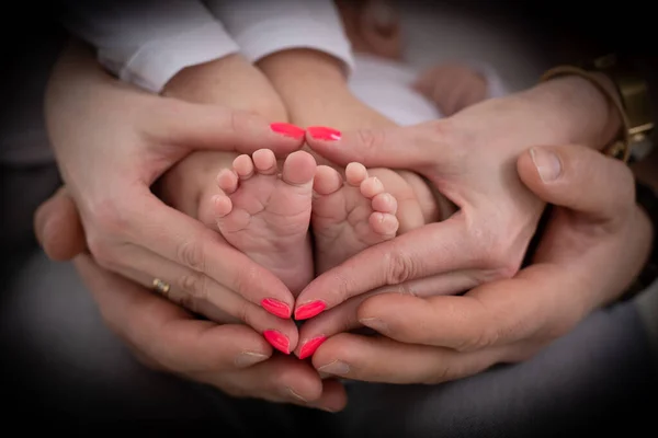 Joven familia irreconocible de madre padre e hijo. Mamá, papá y el niño sostienen las piernas, el pie del bebé recién nacido —  Fotos de Stock