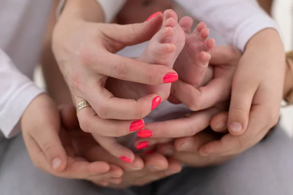 Familia irreconocible de madre padre e hijo. Mamá, papá, el niño sostiene las piernas, el pie de la familia del bebé recién nacido con dos hijos —  Fotos de Stock