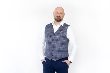 Kendine güvenen orta yaşlı işadamının portresi gri kareli yelek, beyaz gömlek, mavi kot, ayakta, poz. 