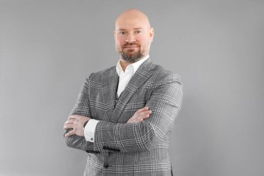 Gri kareli ceketli, beyaz gömlekli, kolları çaprazlanmış gülümseyen orta yaşlı işadamının portresi..