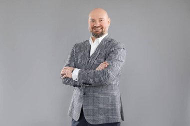 Gri kareli ceketli, beyaz gömlekli, kolları çaprazlanmış neşeli orta yaşlı işadamının portresi..