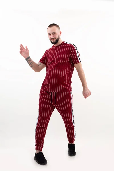 Retrato de jovem feliz bonito barbudo homem com curto escuro cabelo vestindo vermelho listrado esporte desgaste, levantando a mão para cima, posando. — Fotografia de Stock