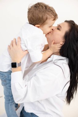 Bekar bir annenin dikey portresi. Koyu saçlı bir kadın. Oğlu, sarılıyor, dudaklarını öpüyor ve sarılıyor.