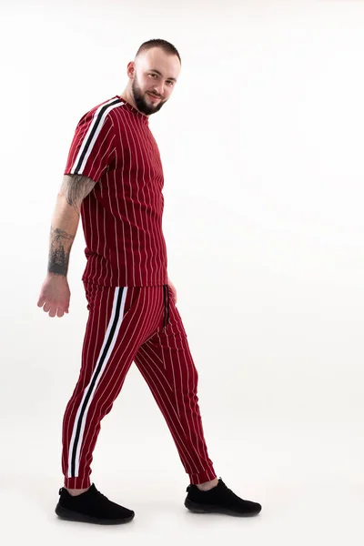 Portrait of young smiling bearded man with short dark hair wearing red striped sport wear, standing on white background. — 스톡 사진