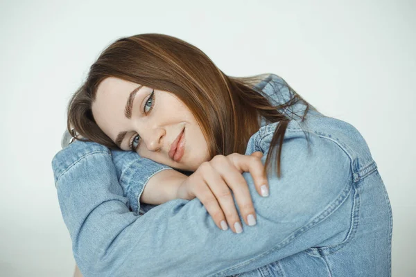 Beautiful happy woman with brown hair and natural makeup posing and wearing seasonal blue denim jacket closeup, white background. Glamour fashion style catalog of casual clothes for young ladies —  Fotos de Stock