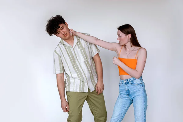 Portrait of young couple posing on white background. Young angry displeased woman punching beating tired exhausted man. — Foto Stock