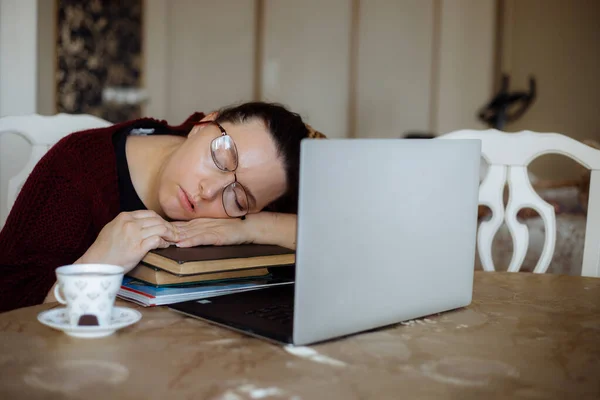 피곤 한 젊은 여자 가 거실 책상에 있는 노트북 근처의 책 들에서 잠을 자고 있는 모습. 단조 로운 공부로부터 피곤 함을 느끼고 컴퓨터 과로 로인하여 직장에서 휴식을 취한다. 에너지 동기의 부족 — 스톡 사진