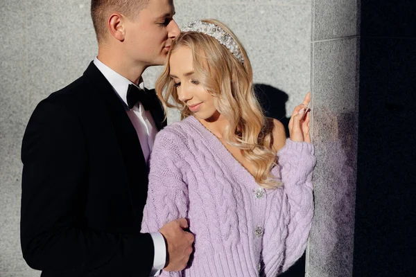 Beautiful young wedding couple in elegant clothes walk around city, kiss and hug on street background. Portrait closeup of happy bride and groom in love. Wedding day, family holiday — Foto de Stock