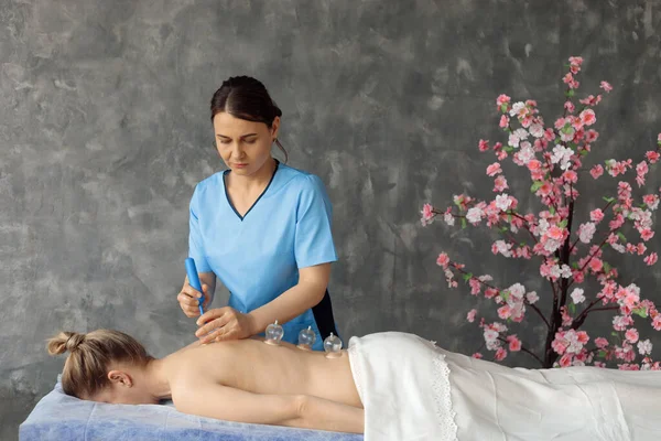 Dolap masörü, elinde elektrikli süpürgeyle koltuğa uzanmış kadın kaslarına masaj yapıyor. Uzman resepsiyonu, profesyonel masaj ve klinikte rahatlama. Kaplama ve tedavi kavramı — Stok fotoğraf