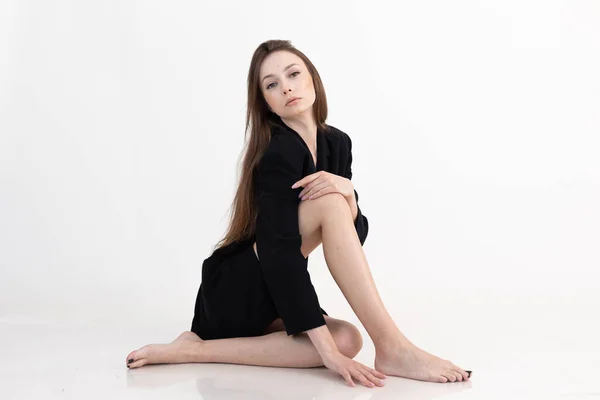 Attractive barefoot brown long-haired woman in black on white studio background. Skin care, spa hair removal procedures — ストック写真