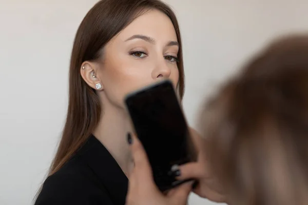 Close up photo of unrecognizable woman hands with smartphone taking photo of elegant fashion model face with make up — Foto de Stock