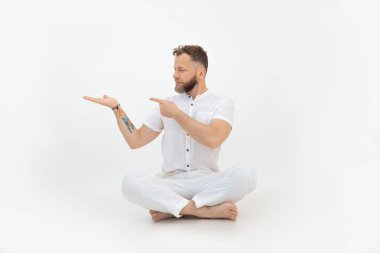 Dövmesi olan yakışıklı, beyaz tenli bir adam yerde oturuyor. Boş alanı elinizin altında tutun. Reklam ürünü