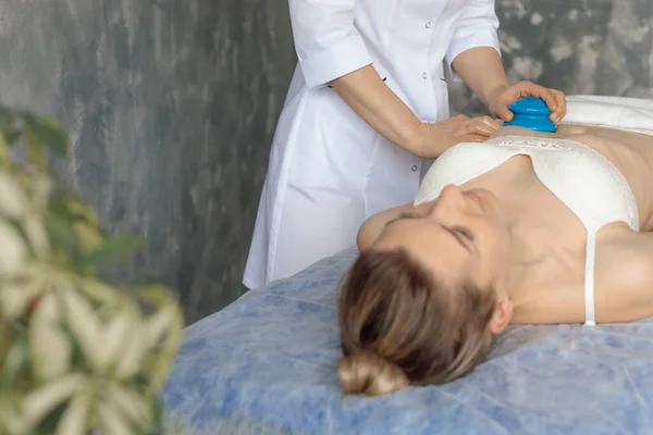 Çin kavanozuyla kanepeye uzanmış çıplak bir kadının göbeğine masaj yapan bir masör. Uzman resepsiyonu, profesyonel masaj ve spa salonunda rahatlama. Sağlık ve antikelülit tedavisi — Stok fotoğraf