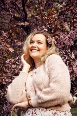 Büyük güzel leylak çiçekleri içindeki kaygısız gülümseyen sarışın kadının dikey görüntüsü bir ağaç gibi dallanır. Doğayla uyum ve birlik. Baharda ya da yaz bahçesinde, park. Hafta sonları boş zaman aktivitesi