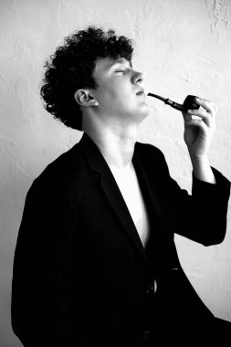 Dikey siyah beyaz portre. Siyah kıvırcık saçlı genç adam. Gözlerini kaybetmiş. Retro tarzı. Çıplak vücudunda siyah ceketi olan çekici ve yakışıklı bir adam. Şehir biçimi