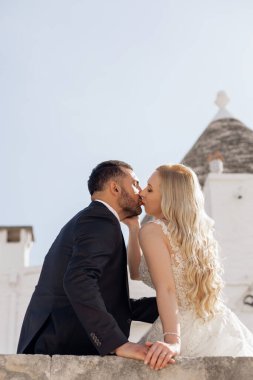 Dikey yakın plan evli çift, güzel sarışın kadın, gelin ve koyu saçlı sakallı adam, damat birlikte öpüşüyor, dokunuyor, sarılıyor. Yeni bir aile, sevgi ve şefkat yarat. Düğün töreni. Boşluğu kopyala