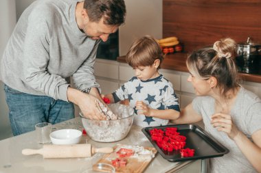 Baba, oğlum ve annem mutfakta kurabiye hamuru yapmakla meşguller. Aileler birlikte eğlenir, hobileri olur, takım çalışması olur. Mutlu İnsanlar. Evde yemek pişirmek..