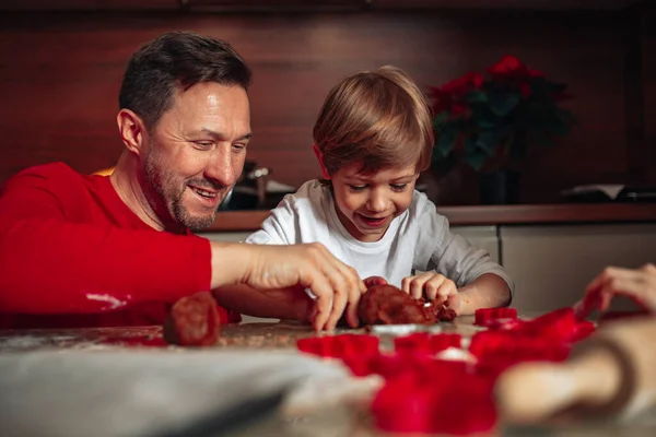Son and dad. Little boy is happy to spend time with his father. Cookies are baked in kitchen at home. Happy moments of Christmas. People are having fun. Happy family. Joint activity. Cooking at home.