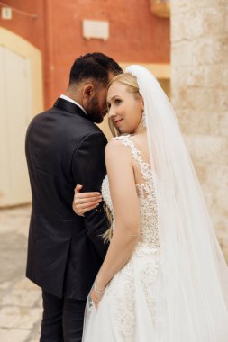 Mutlu, yakın romantik çiftin dikey portresi, sarışın kadın ve siyah saçlı adam düğünden sonra, aşırı giyinmiş, kucaklayıcı, birlikte durun. İtalya tatili, tören için yurt dışına seyahat.