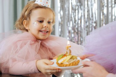 Doğum günü beş yıllıktır. Çekici, şen şakrak giyinmiş, gülümseyen kız doğum günü pastasıyla tabağı kaldırıyor ve beş numara. Çocuklar, mutlu duygular. Mutluluk ve kutlama. Harika anlar. 