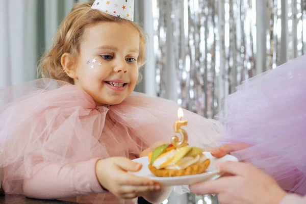 Doğum günü beş yıllıktır. Çekici, şen şakrak giyinmiş, gülümseyen kız doğum günü pastasıyla tabağı kaldırıyor ve beş numara. Çocuklar, mutlu duygular. Mutluluk ve kutlama. Harika anlar. 