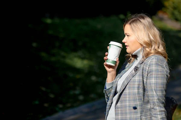 Wonderful moments of relaxation with recyclable cup of hot drink in city park on sunny autumn day for blonde in jacket. Femininity and elegance. Life in moment. Walking in fresh air.
