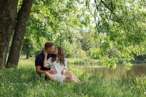 可爱的年轻夫妇坐在湖边的树下 彼此凝视着 年轻男女享受夏日 恋爱中的快乐人 甜蜜的月亮 — 图库照片