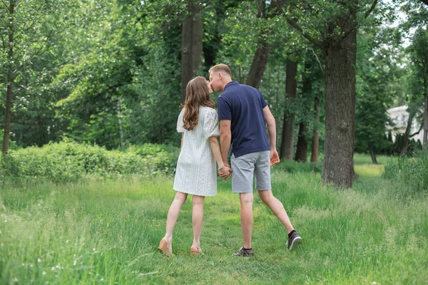 侧向后看全长肖像的激情浪漫的年轻夫妇亲吻和拥抱步行在绿地公园度假 有浪漫周末 生活方式和爱情的年轻人 — 图库照片