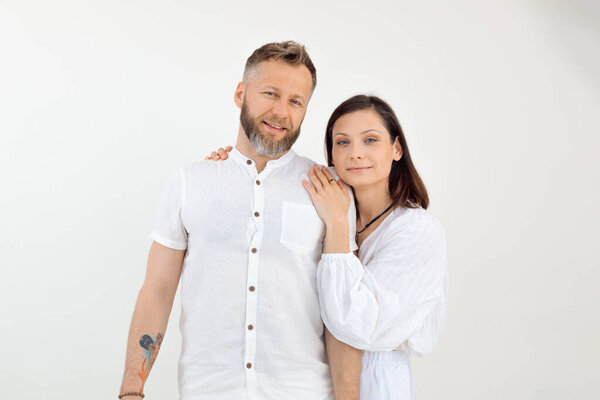 Мужчина с татуировкой и женщиной, семья, стоящая вместе, обнимающаяся, одетый в белую одежду на изолированном фоне. Доверие и любовь. Поддерживать друг друга, как любящие партнеры. Смотри в камеру.