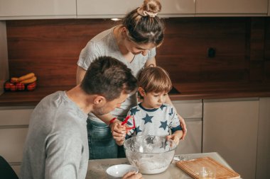 Anne, baba ve oğul mutfak ve takım çalışması için hazırlanıyor. Mutlu saatler genç aile, baba ve çocuk, ebeveynler ve çocuk. Mutlu insanlar. Birlikte yemek pişirmek.