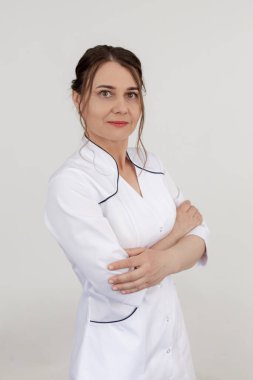 Beyazlar içindeki dikey kendine güvenen kadın doktor, beyaz stüdyodaki kameraya bakıyor. Kozmetoloji ve vücut masajı. Fizyoterapist, sağlık görevlisi, hemşire, kaplıca salonunda ortopedist..