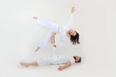 Active, sportive happy family of man and woman practicing yoga as couple. Male holding woman side like star in the air on one leg. Healthy lifestyle and family sport activity on white studio back view