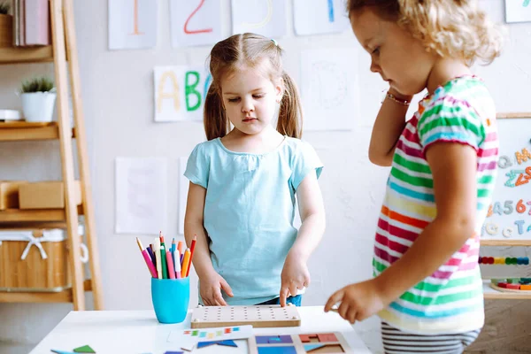 Two Concentrated Cute Little Girls Children Pupils Standing White Table — Zdjęcie stockowe