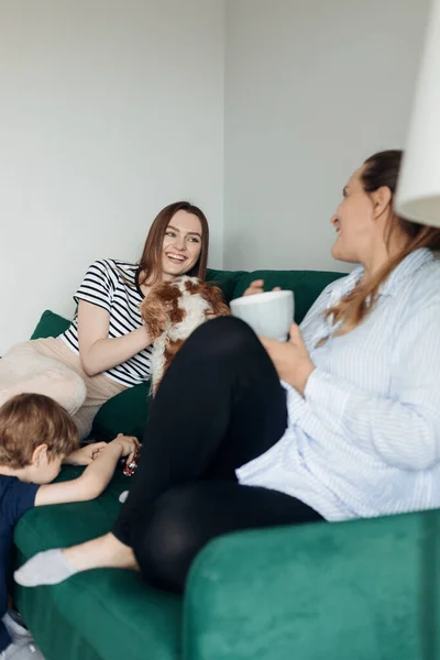 Vertical Laughing Young Woman Sitting Green Sofa Talking Female Friend — Zdjęcie stockowe