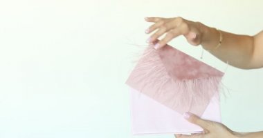 Kırpılmış eller pembe yumuşak tekstil zarf zarfına dokunup sarıyorlar ve beyaz arka planda diğer ellere geçiyorlar. Özel romantik hediye, tatillerde gönderilen aşk mektubu. Boşluğu kopyala